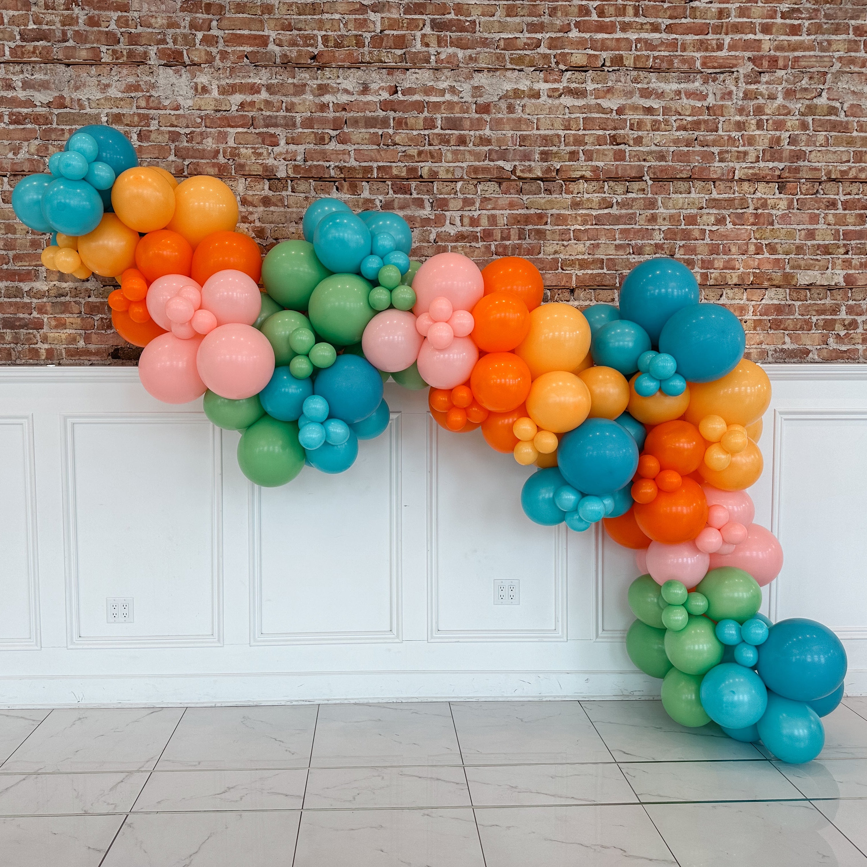 Colorful balloon garland against a brick wall