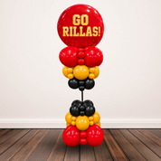 A freestanding balloon column decoration with a large red round balloon at the top printed in yellow text reading 'GO RILLAS!' and alternating red, yellow, and black balloon clusters below, shown against a plain wall and wood floor.