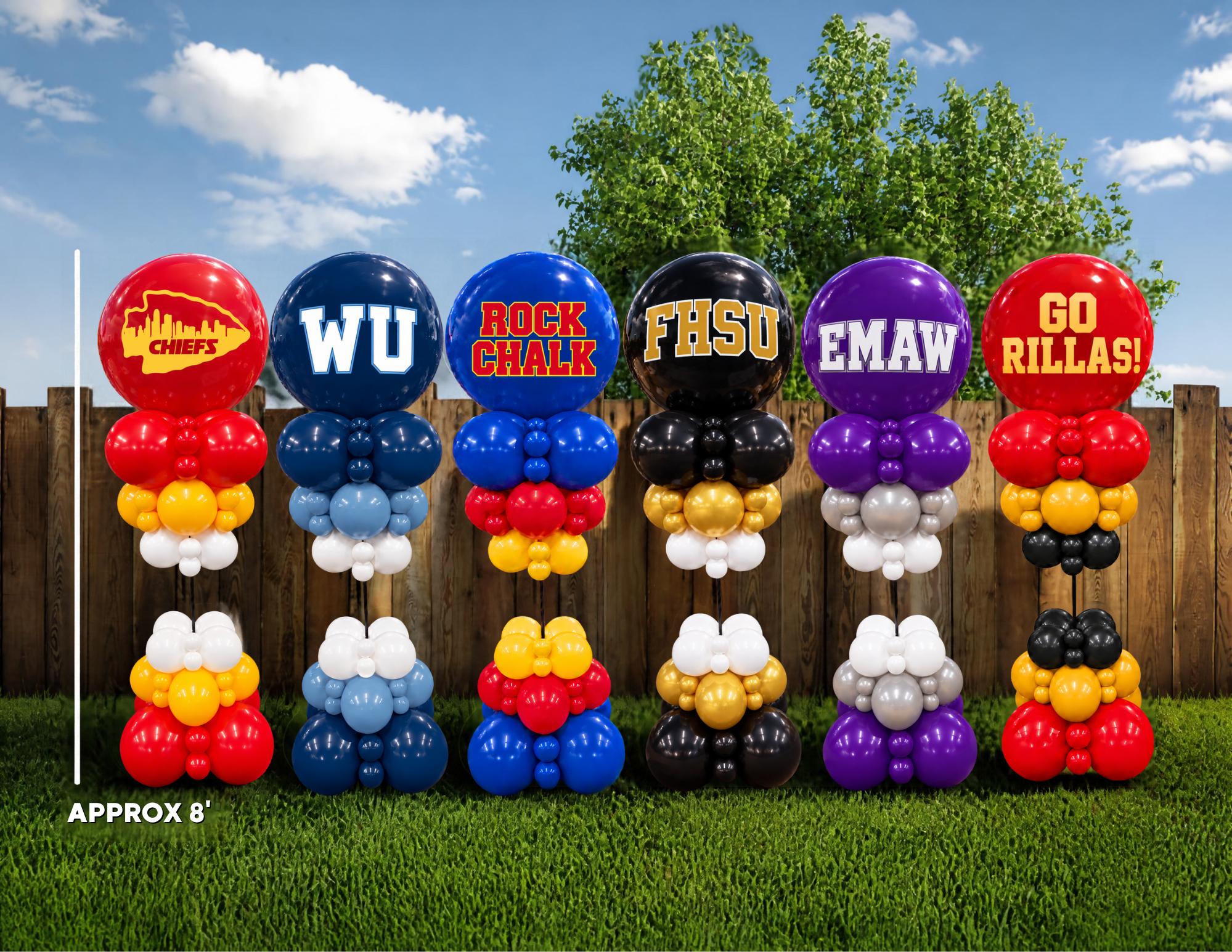 Six custom balloon garland stands displayed on a green lawn in front of a wooden fence and trees. Each stand features a large balloon with a school or team logo and colors, with smaller balloons stacked below.