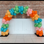 Colorful balloon arch against a brick wall and white paneling.