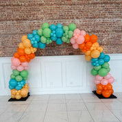 Colorful balloon arch against a brick wall.