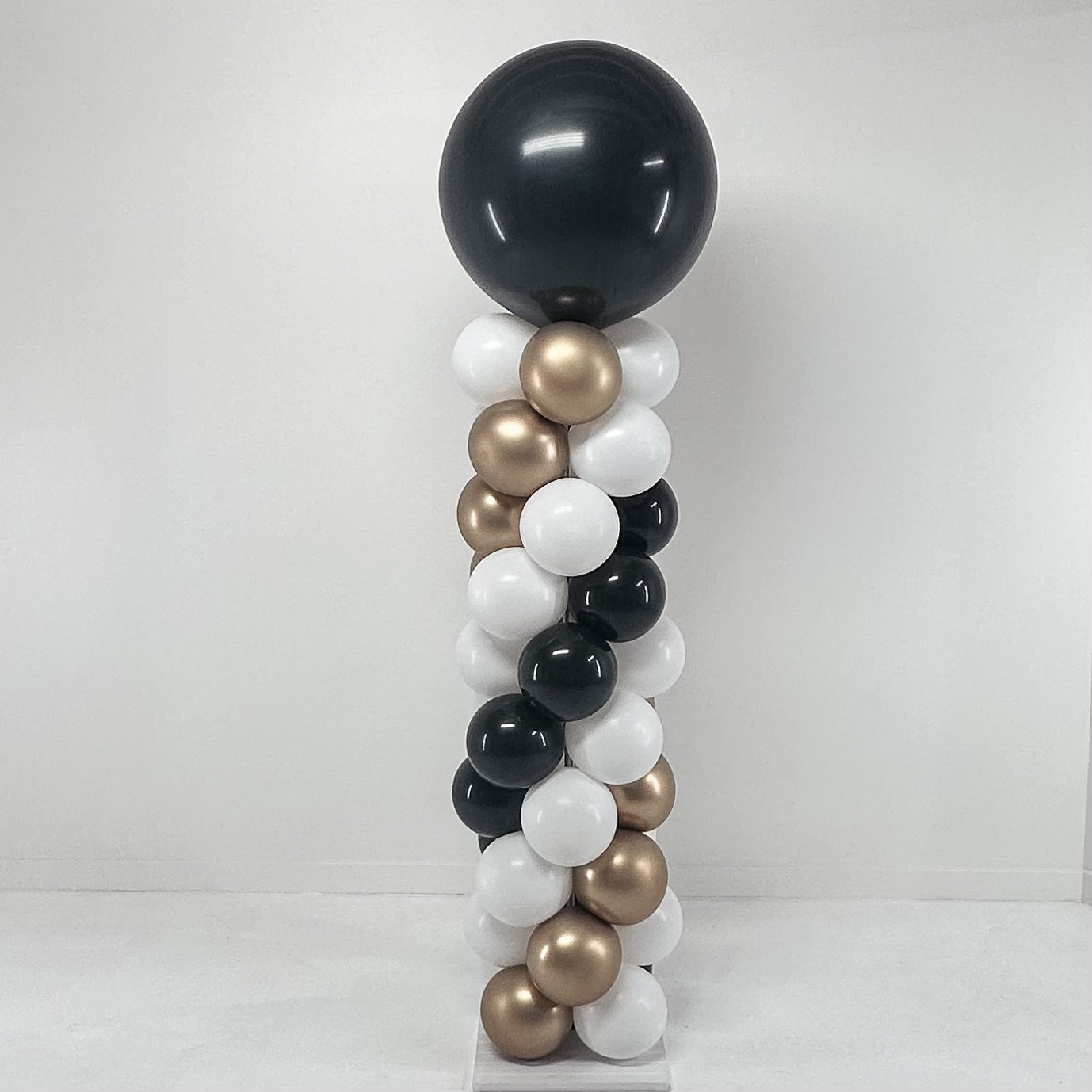 Balloon column with black, gold, and white balloons on a white background